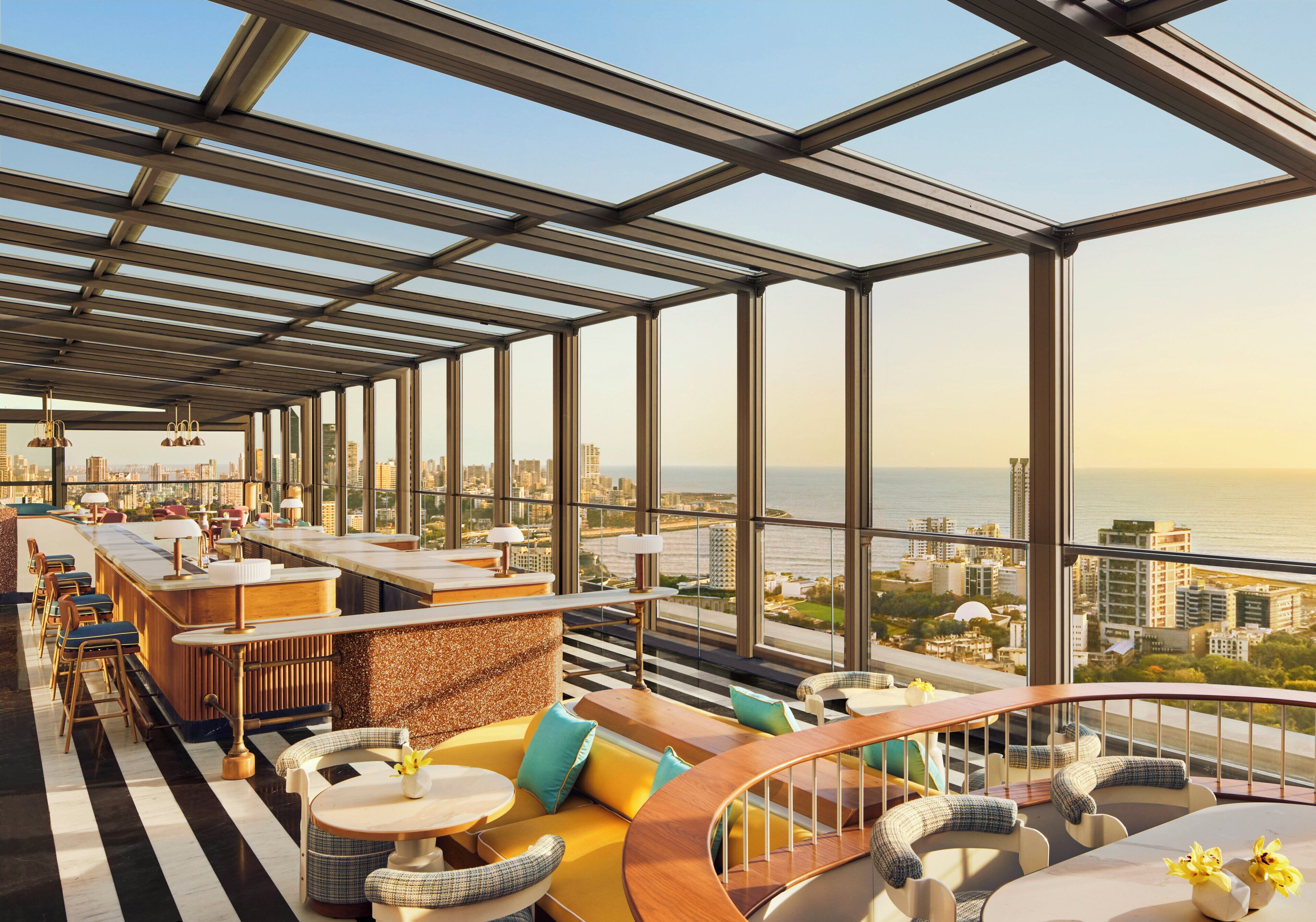 A rooftop bar with a city view, seating arrangements, and a bar counter.