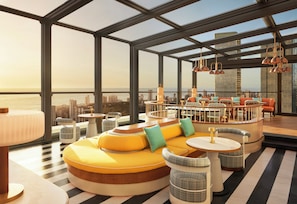 A modern lounge area with seating and tables, large windows with a city view, and hanging pendant lights. - Four Seasons Hotel Mumbai (Mumbai)