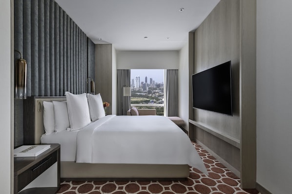 Habitación de hotel con una cama grande, un televisor de pantalla plana y vistas a la ciudad.