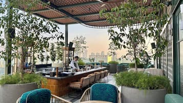An outdoor bar area with seating, a bartender, and a city view.