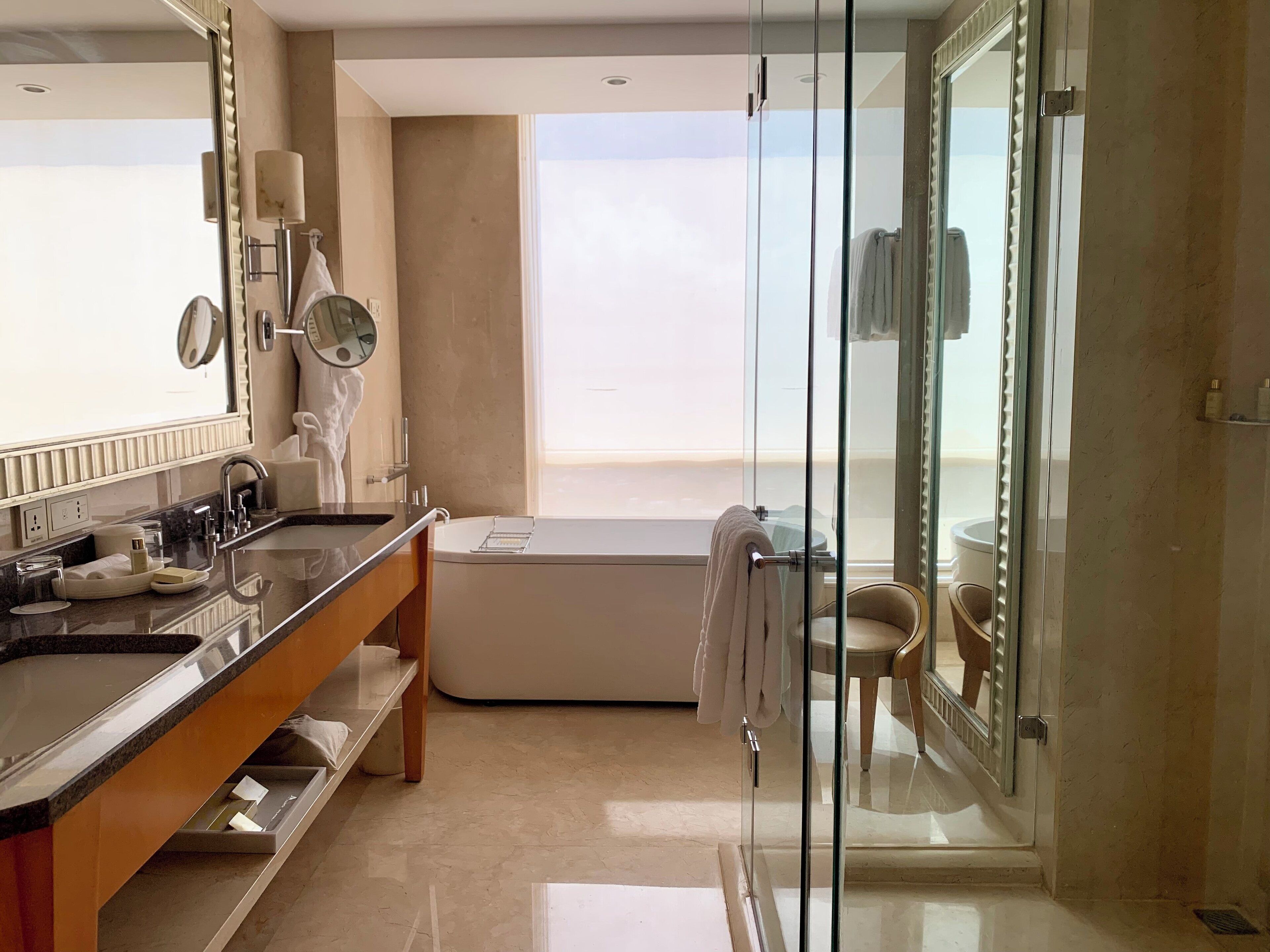 Une salle de bain moderne avec une douche à l’italienne en verre, un grand miroir et une baignoire.