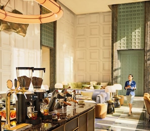 Un vestíbulo de hotel bien iluminado con una barra de café, zona de estar y una persona al fondo.