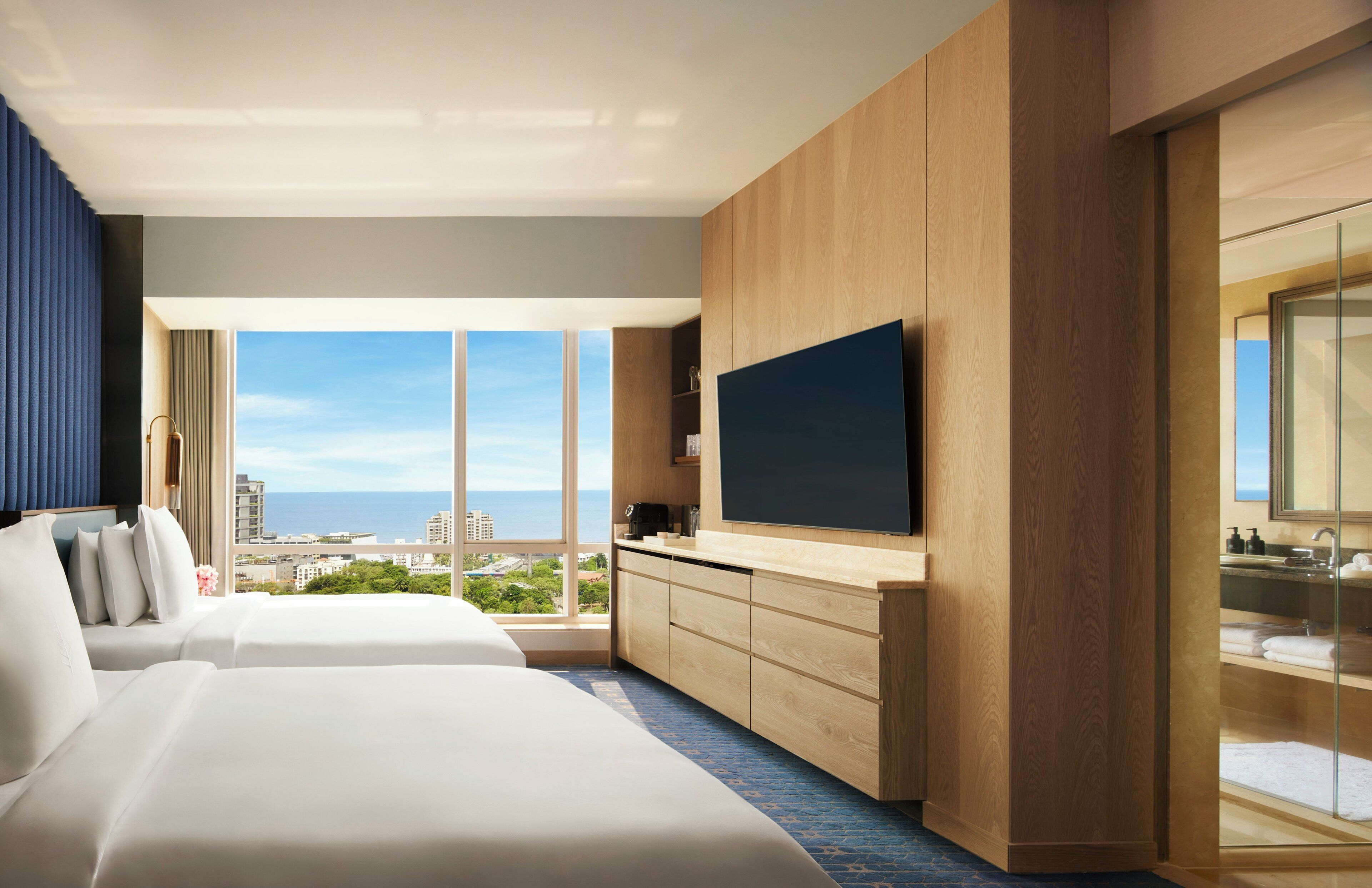 Une chambre d’hôtel avec un grand lit, une télévision, une salle de bain avec un miroir et une vue sur la ville.