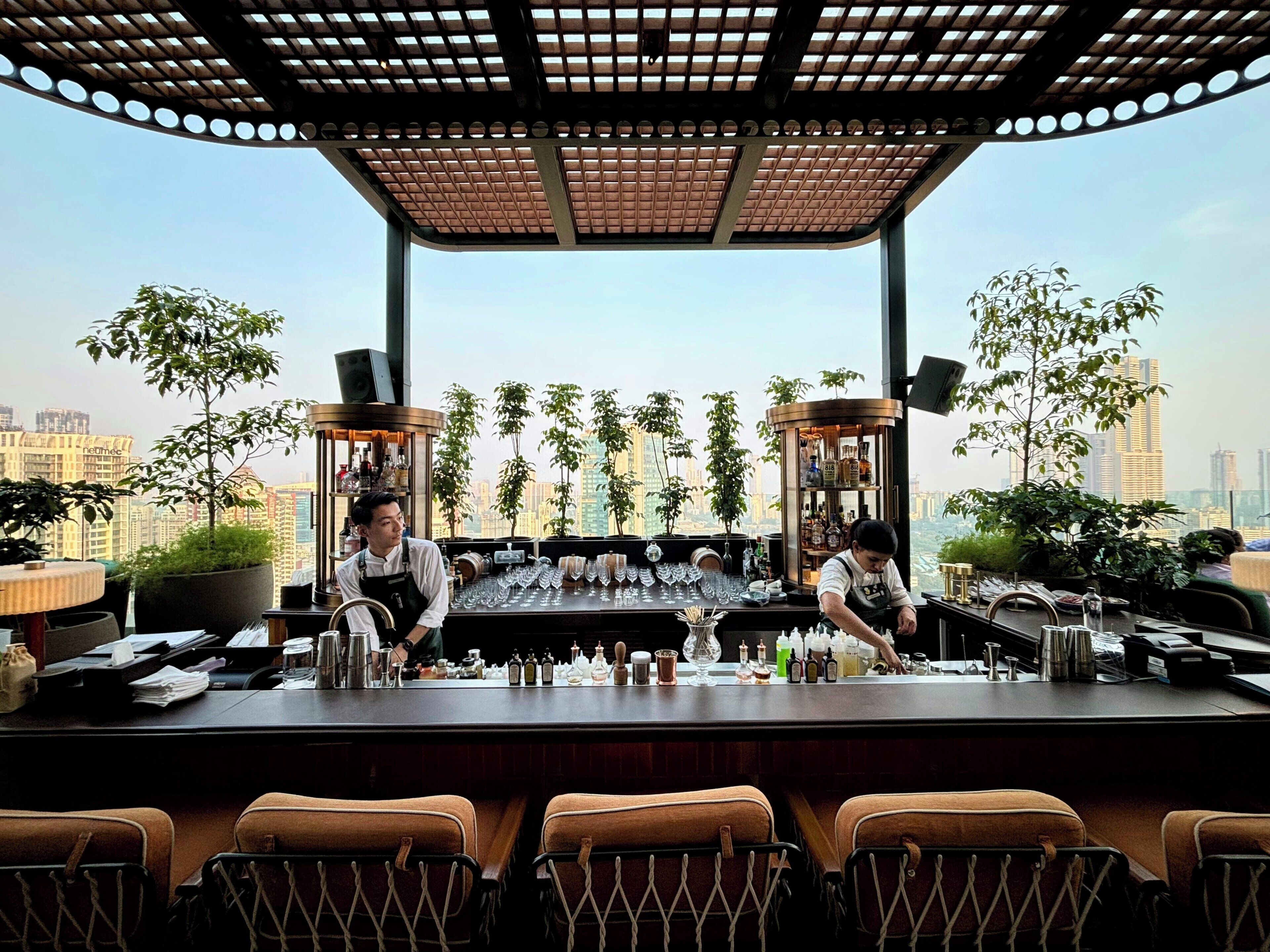 Un bar con due baristi, vista sulla città e arredamento moderno.