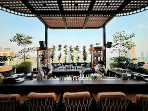 Un bar con dos camareros, vistas a la ciudad y un diseño moderno.