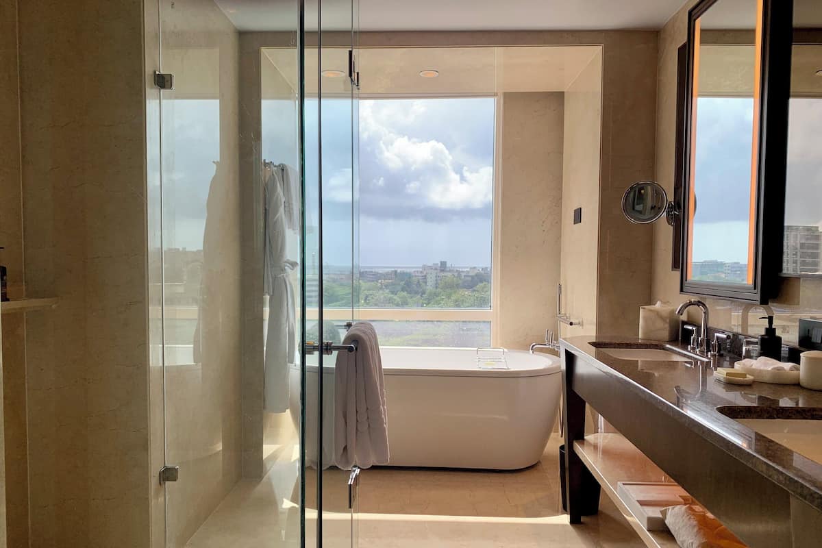 Une salle de bain moderne dotée d’une douche à parois de verre, d’une baignoire sur pieds et d’un meuble-lavabo avec un grand miroir.