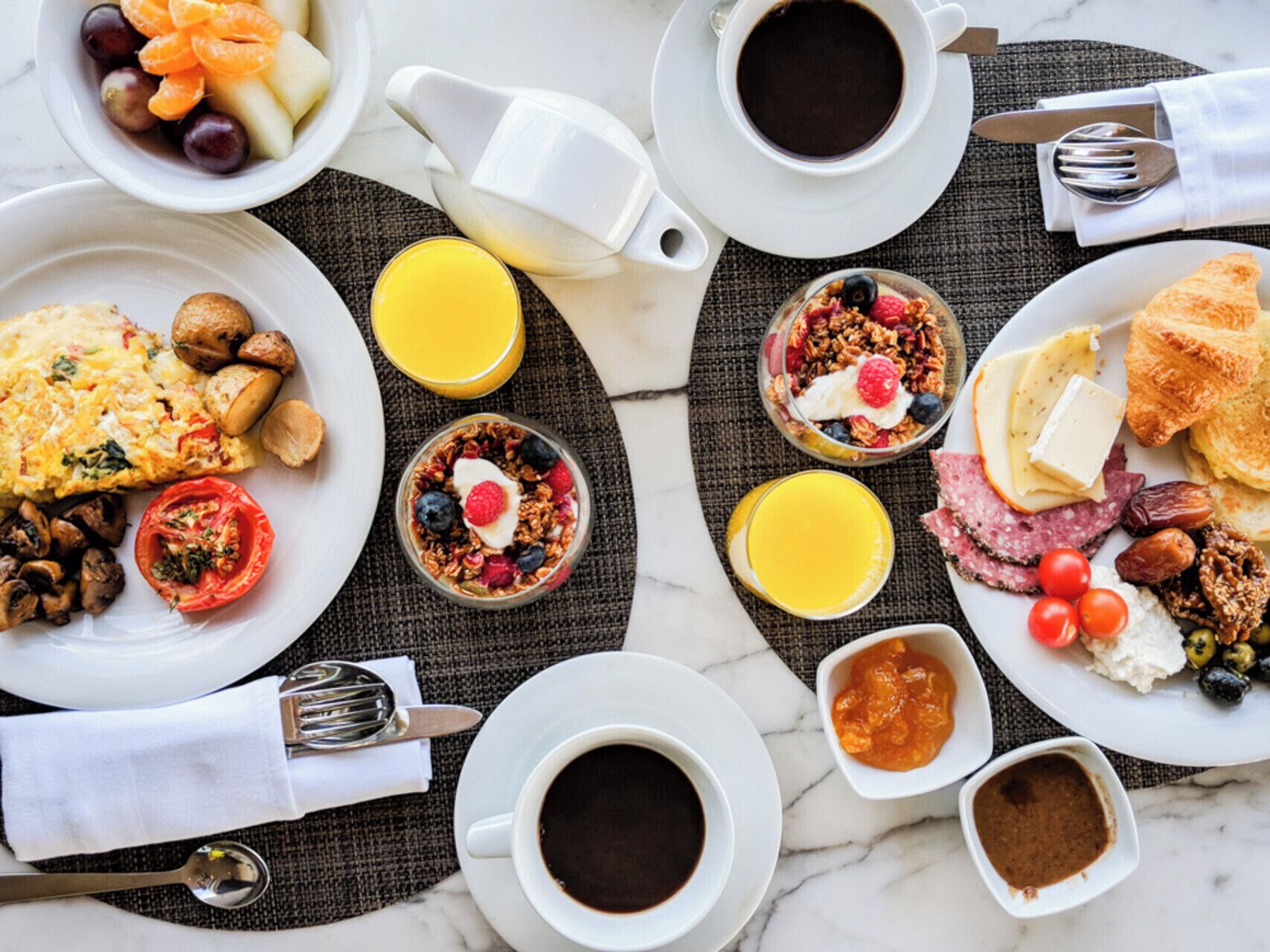 A breakfast buffet with various dishes, including eggs, fruits, and pastries, arranged on a table with coffee and juice.