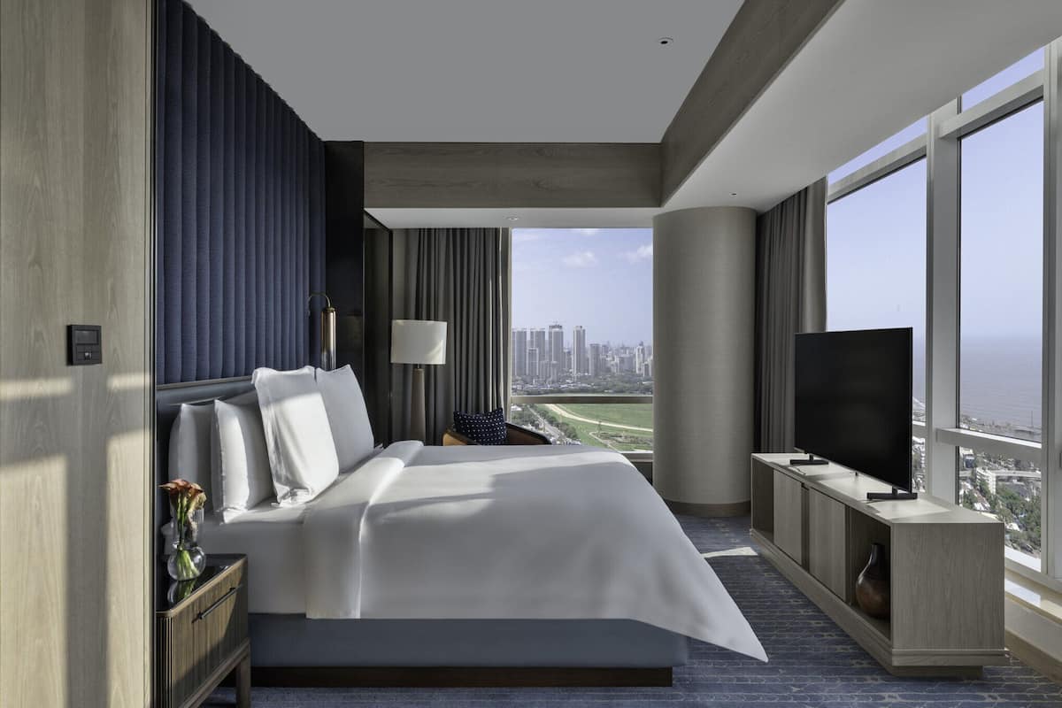 Ein modernes Hotelzimmer mit einem großen Bett, einem Fernseher und Blick auf die Stadtlandschaft.