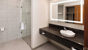 Uma casa de banho moderna com chuveiro de vidro, lavatório de mármore e um espelho grande.