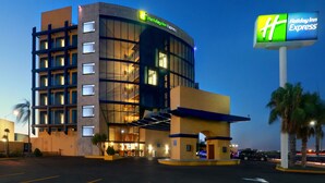 Um hotel Holiday Inn Express com design moderno, destacando uma fachada curva e grandes janelas.
