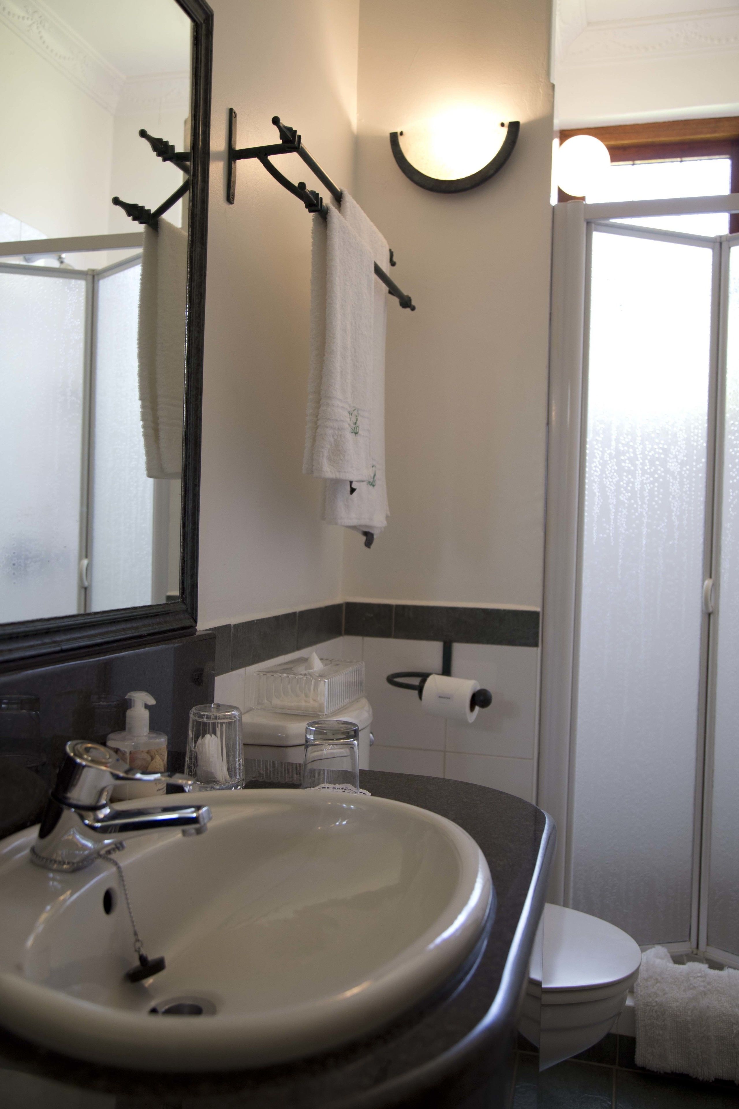 A bathroom with a sink, mirror, towel rack, and toilet.