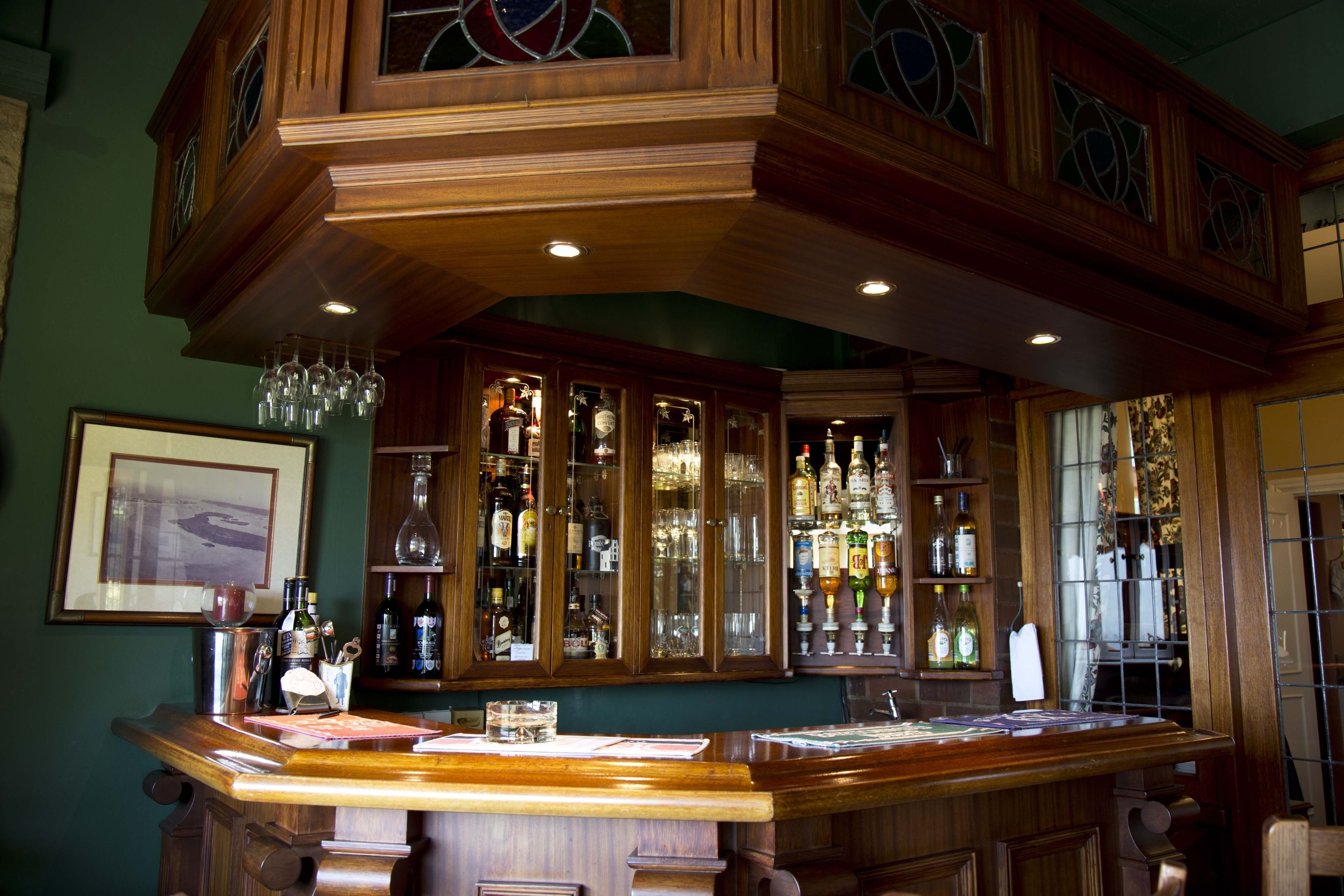 Una zona de bar con armarios de madera, cristalería y botellas.