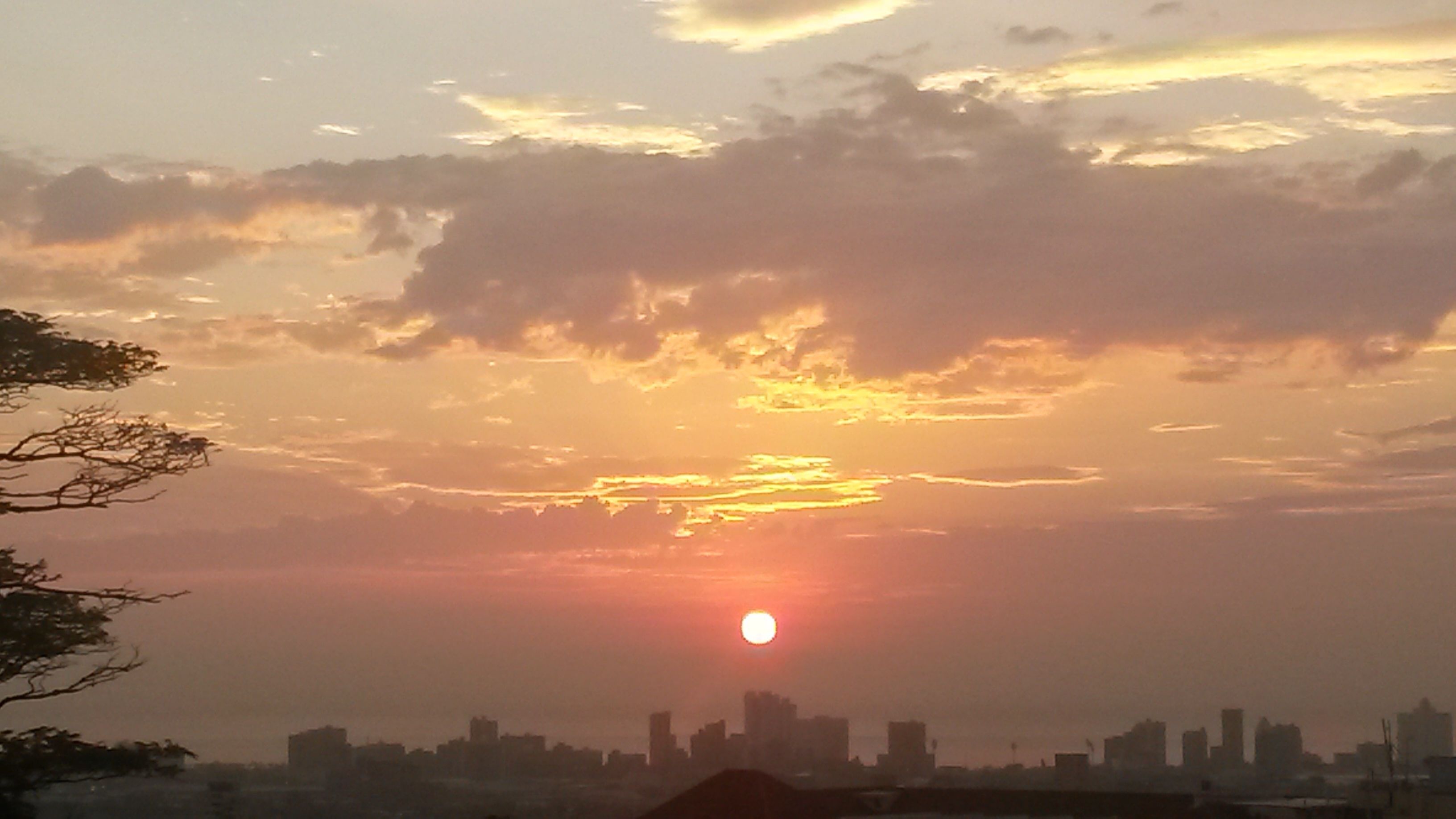 A sunset over a city skyline with buildings silhouetted against the sky.