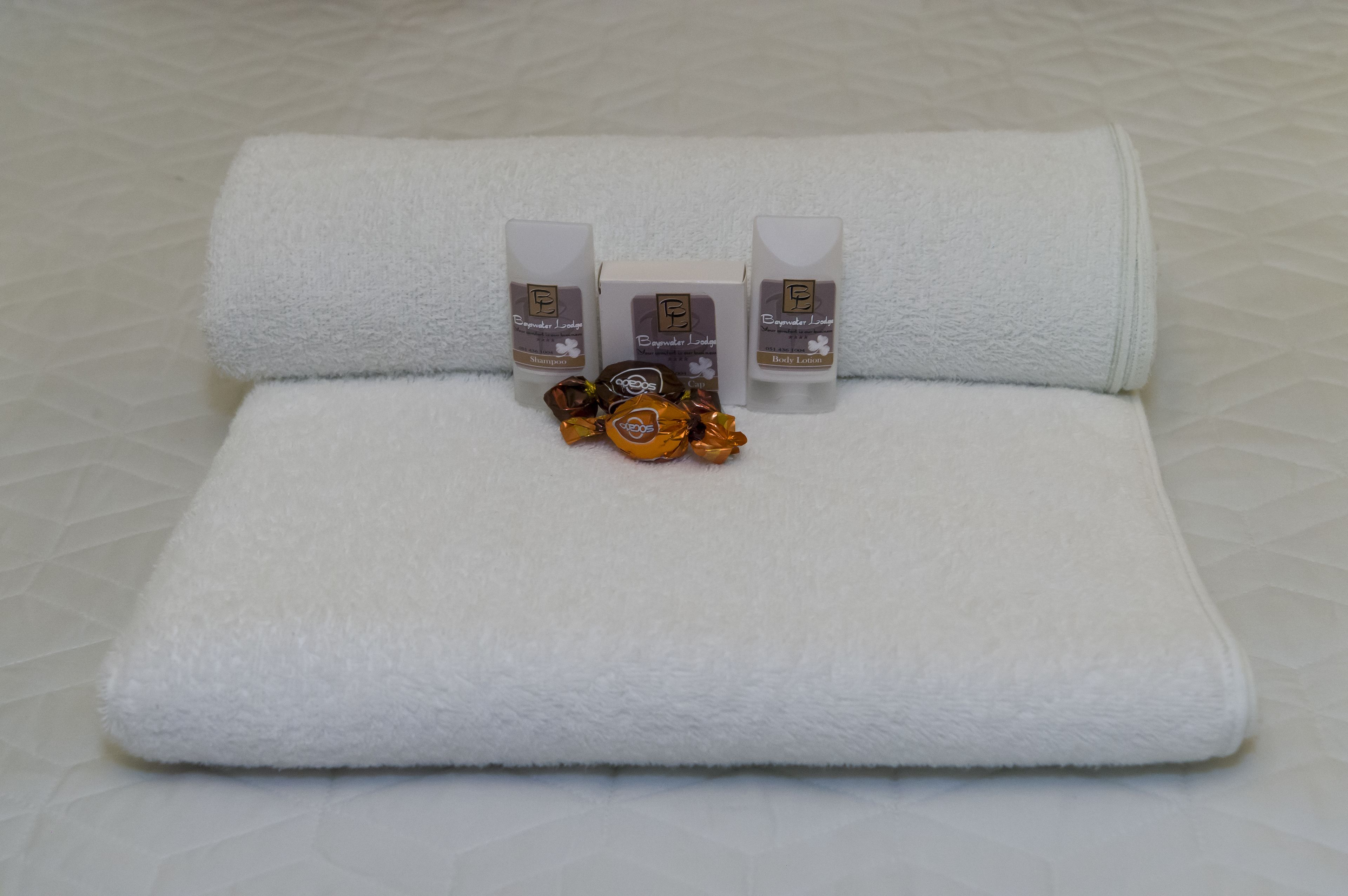 A neatly folded white towel on a textured white surface.
