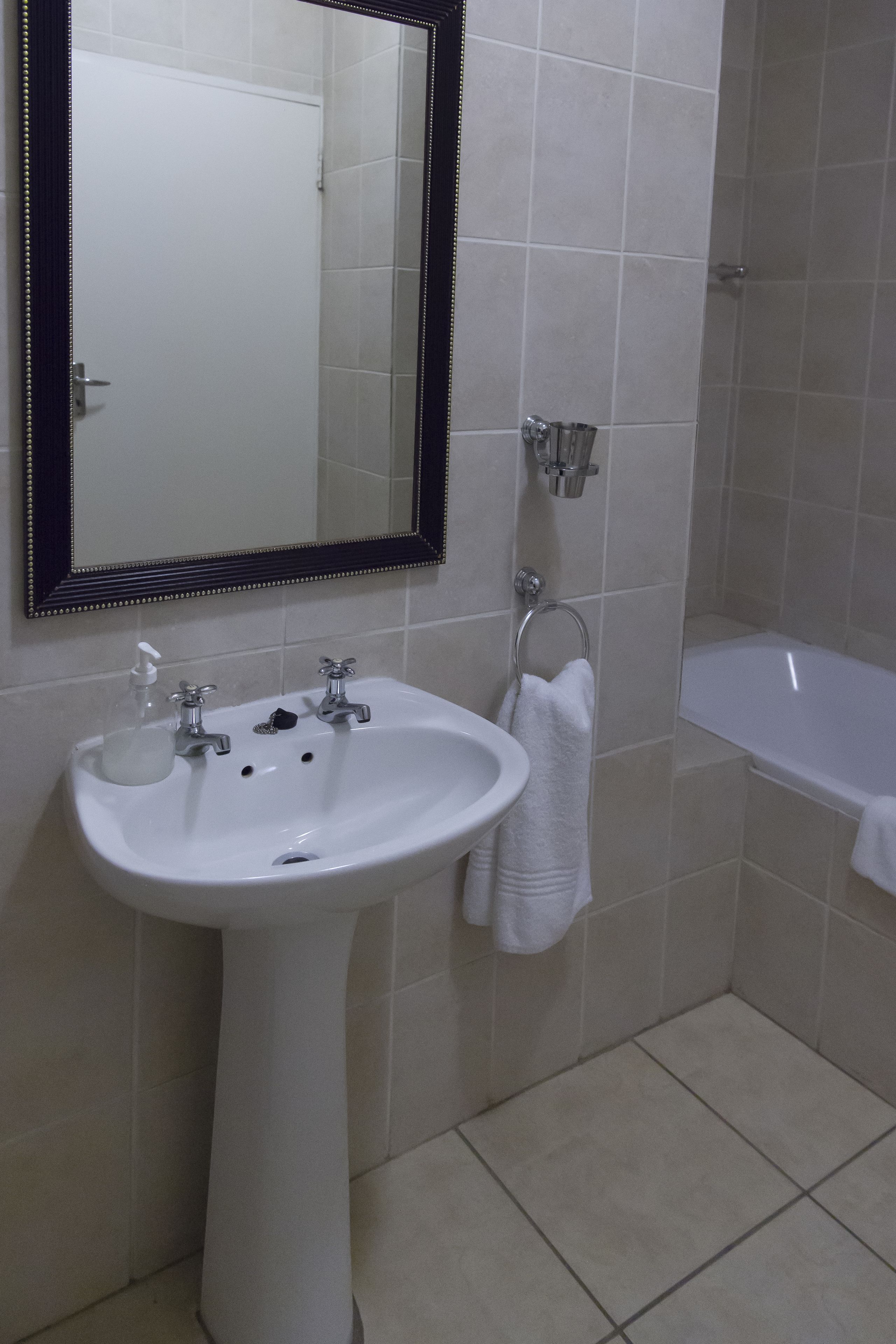A bathroom with a white sink, a mirror, a towel rack, and a bathtub.