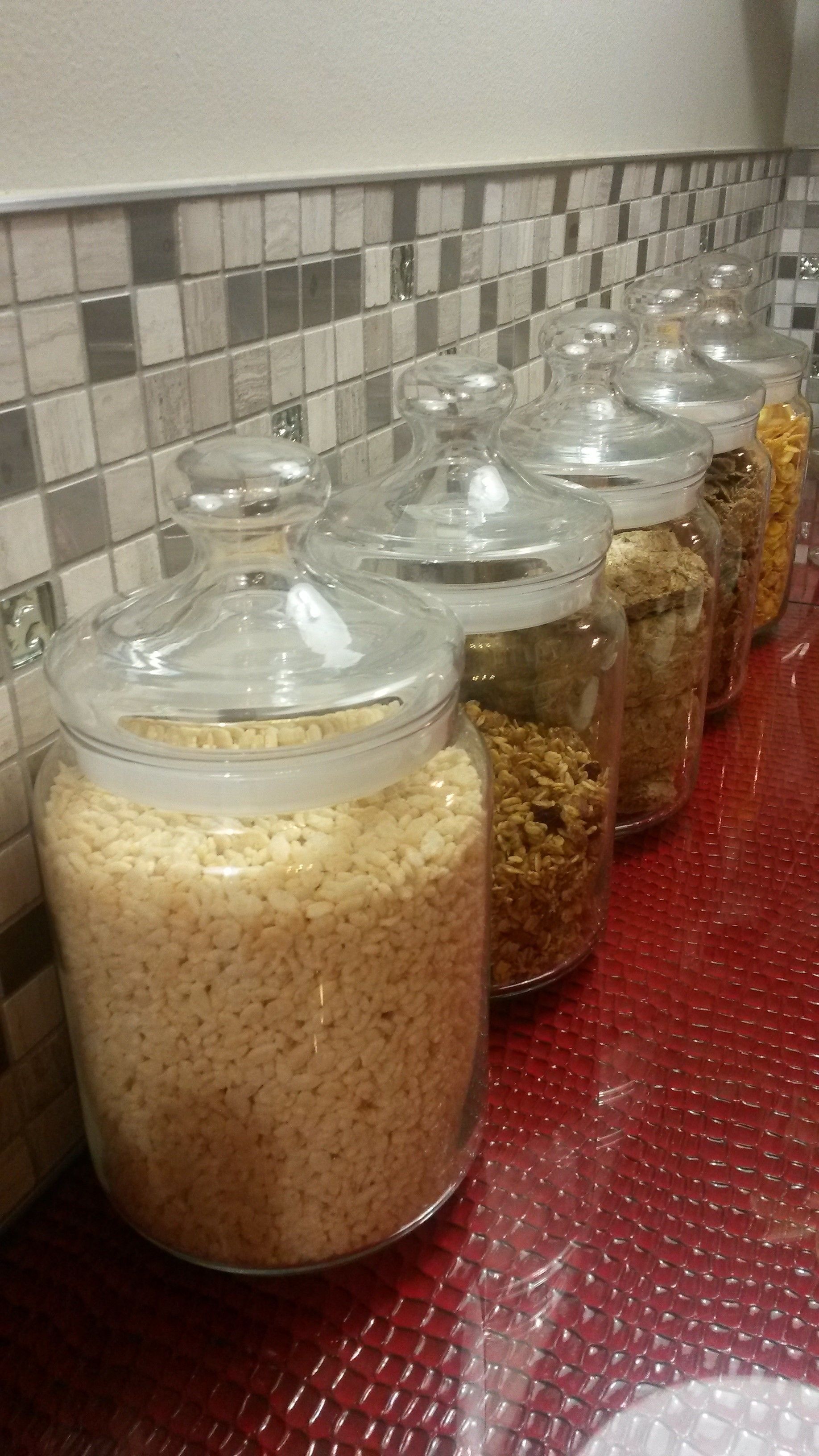 Glass jars with lids containing various grains and seeds on a countertop.