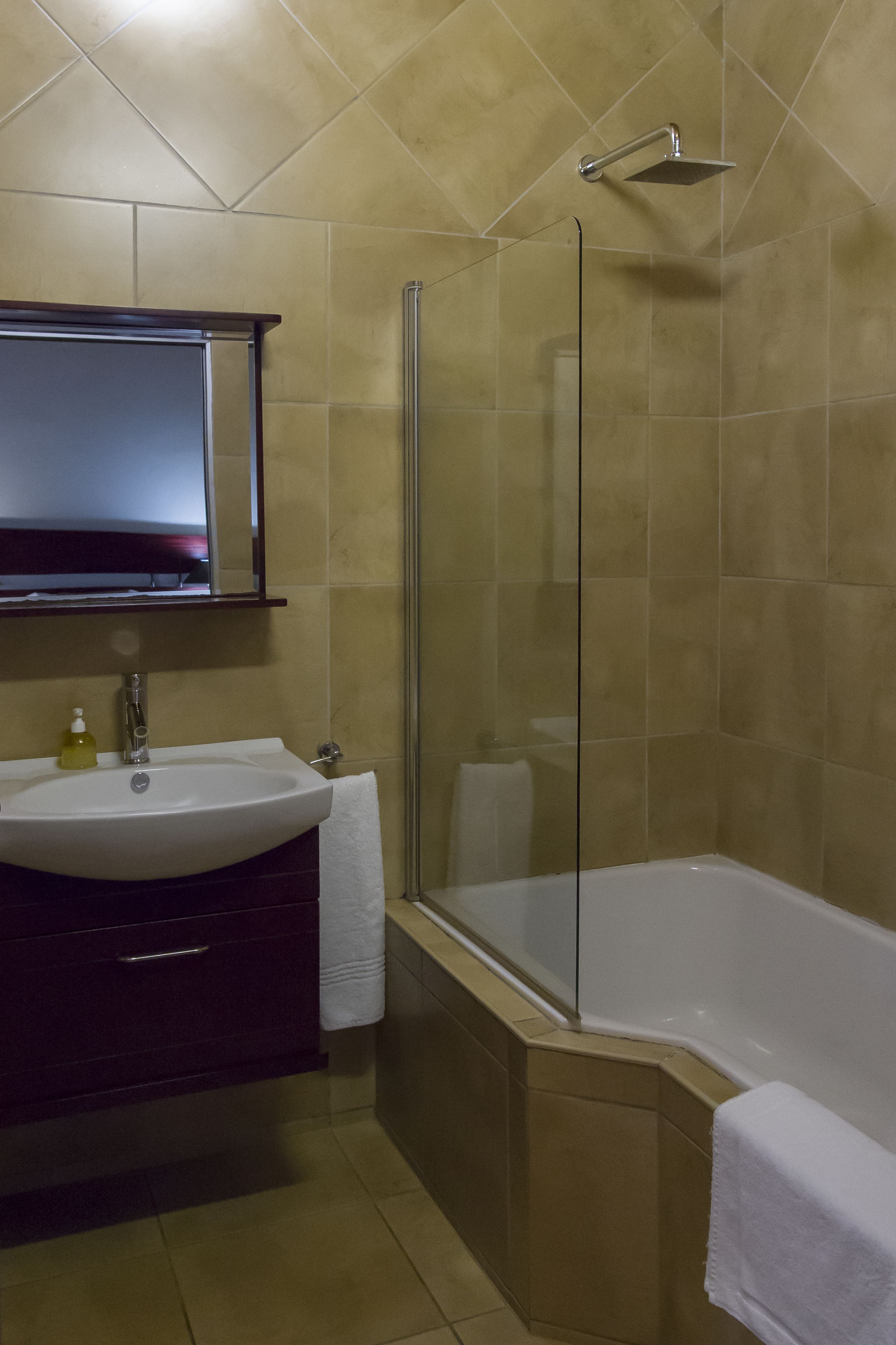 A bathroom with a sink, mirror, and shower.