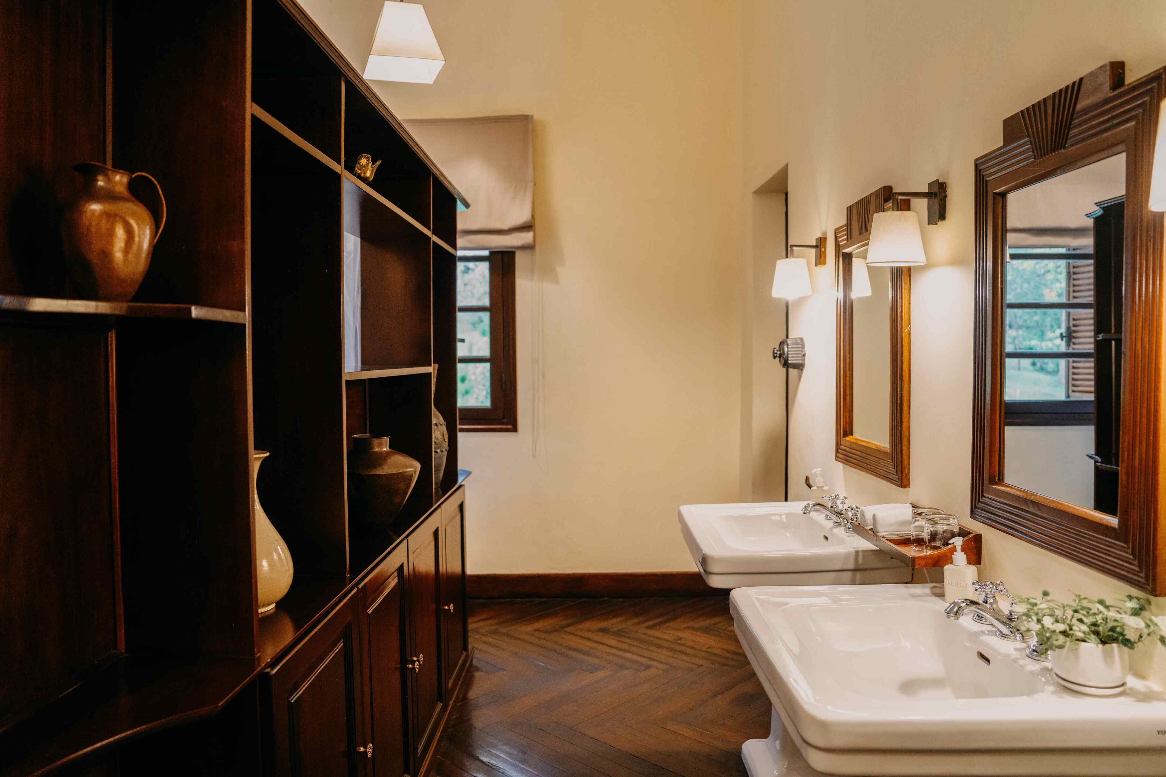 A bathroom with two sinks, wooden shelves, and a mirror.