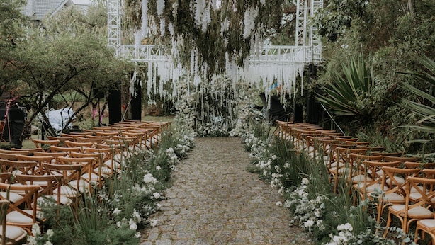 A stone pathway flanked by wooden chairs and white flowers, leading to a white structure. - Ana Mandara Villas Dalat Resort & Spa (Cam Ly - Da Lat)