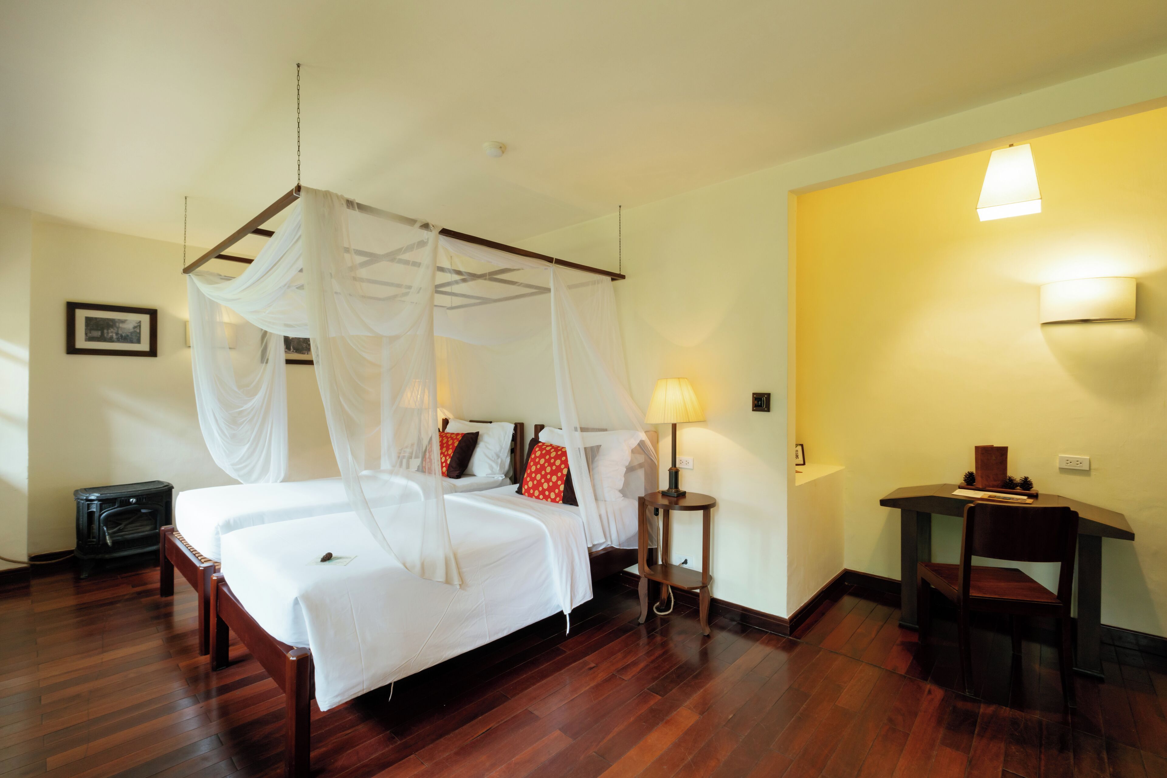 A room with a four-poster bed, a bedside table with a lamp, and a chair.
