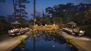 An outdoor dining area with a pool, surrounded by trees and umbrellas. - Ana Mandara Villas Dalat Resort & Spa (Cam Ly - Da Lat)