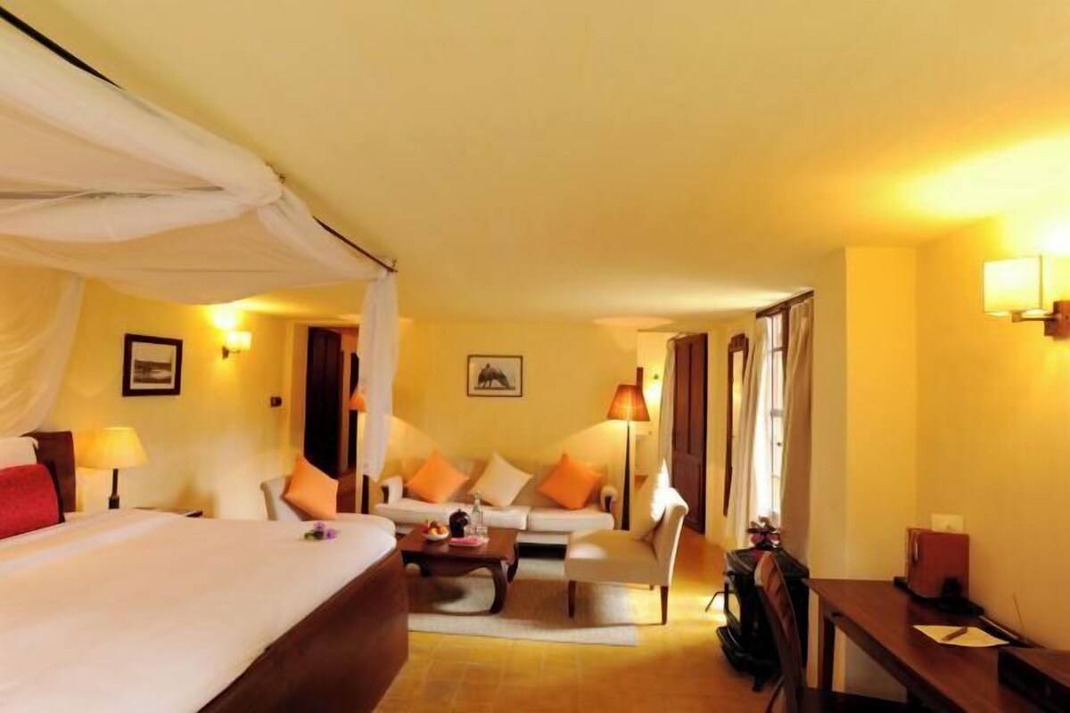 A hotel room with a bed, a sofa, a desk, and a chair.