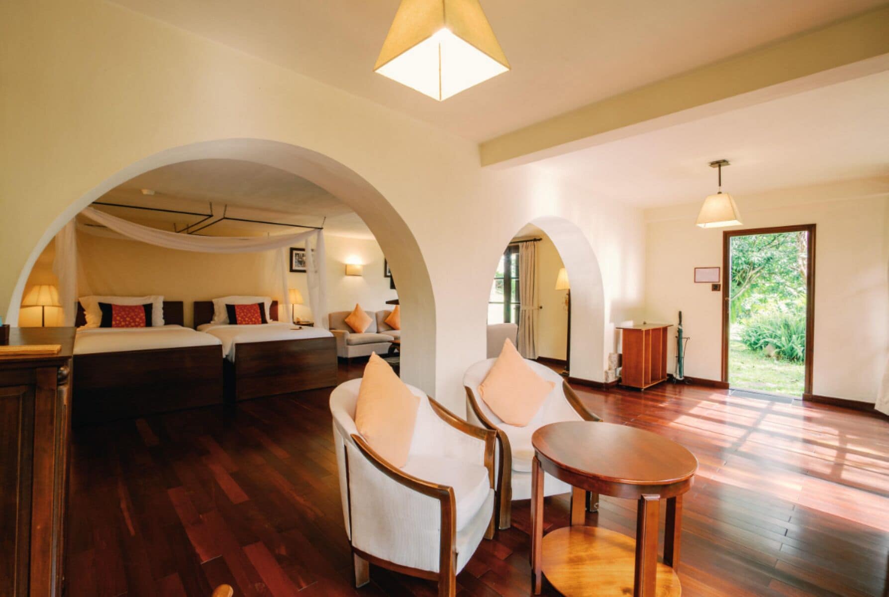 Una habitación amplia con una cama grande, dos sillones, una mesita y suelo de madera.
