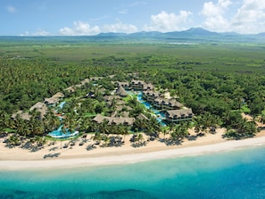 An aerial view of a resort with multiple bungalow-style buildings, a central swimming pool, and a beachfront. - Zoetry Agua Punta Cana - All Inclusive (Punta Cana)