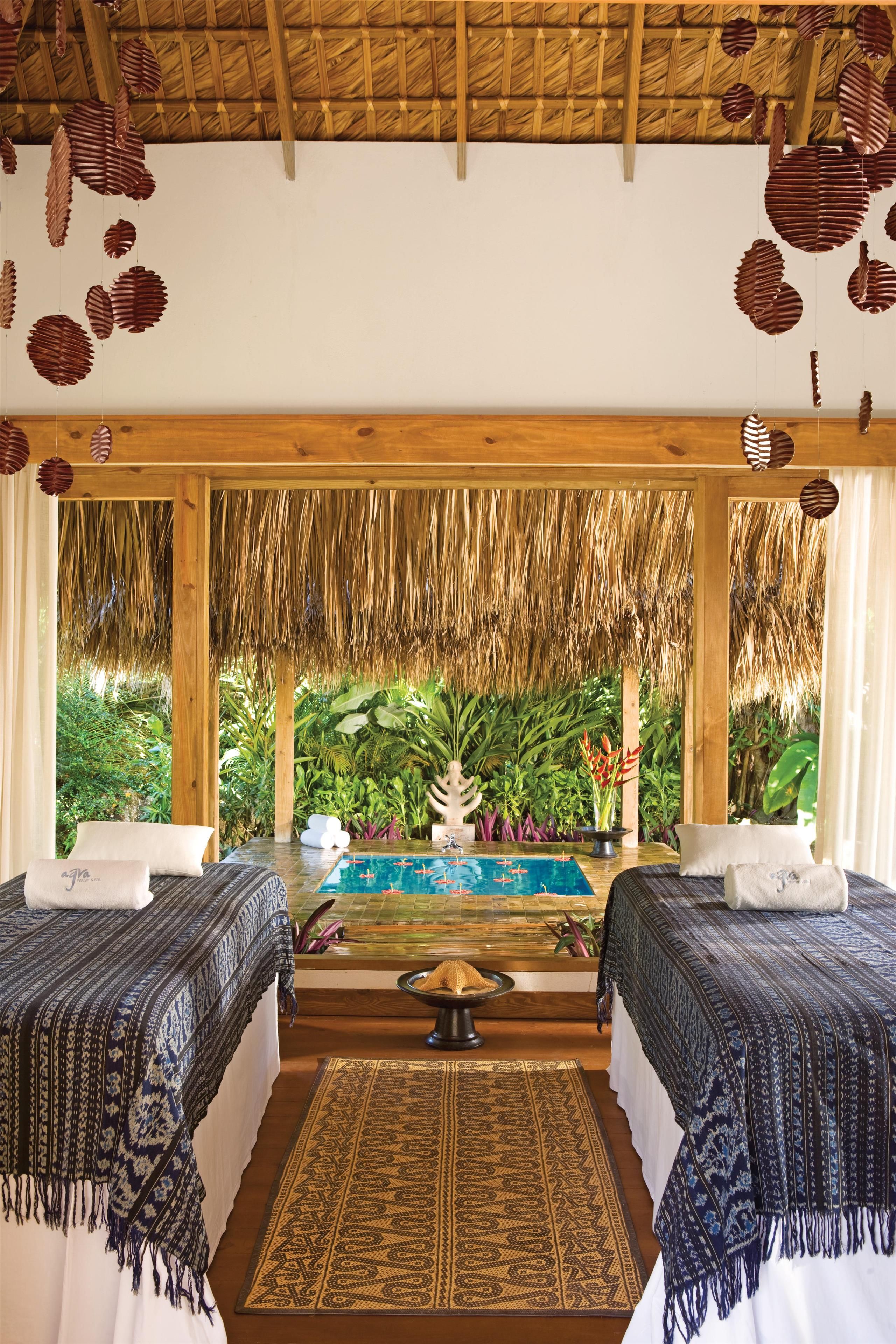 A room with two beds, a pool, and a view of lush greenery.