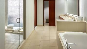 A modern bathroom with a large bathtub, a separate shower area, and a vanity with a mirror.