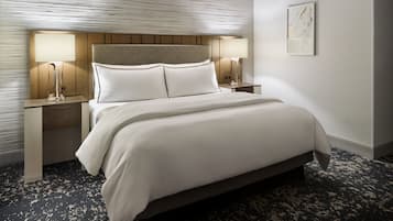 A neatly made bed with white linens, two bedside tables with lamps, and a textured wall.