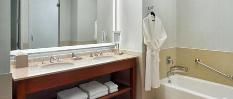 A modern bathroom with a large mirror, a sink, a bathtub, and a towel rack.
