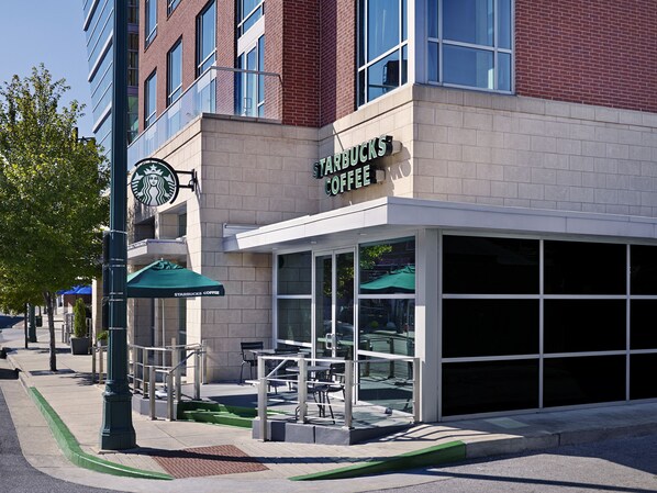 A Starbucks Coffee storefront with outdoor seating and a clear view of the interior through the glass doors.