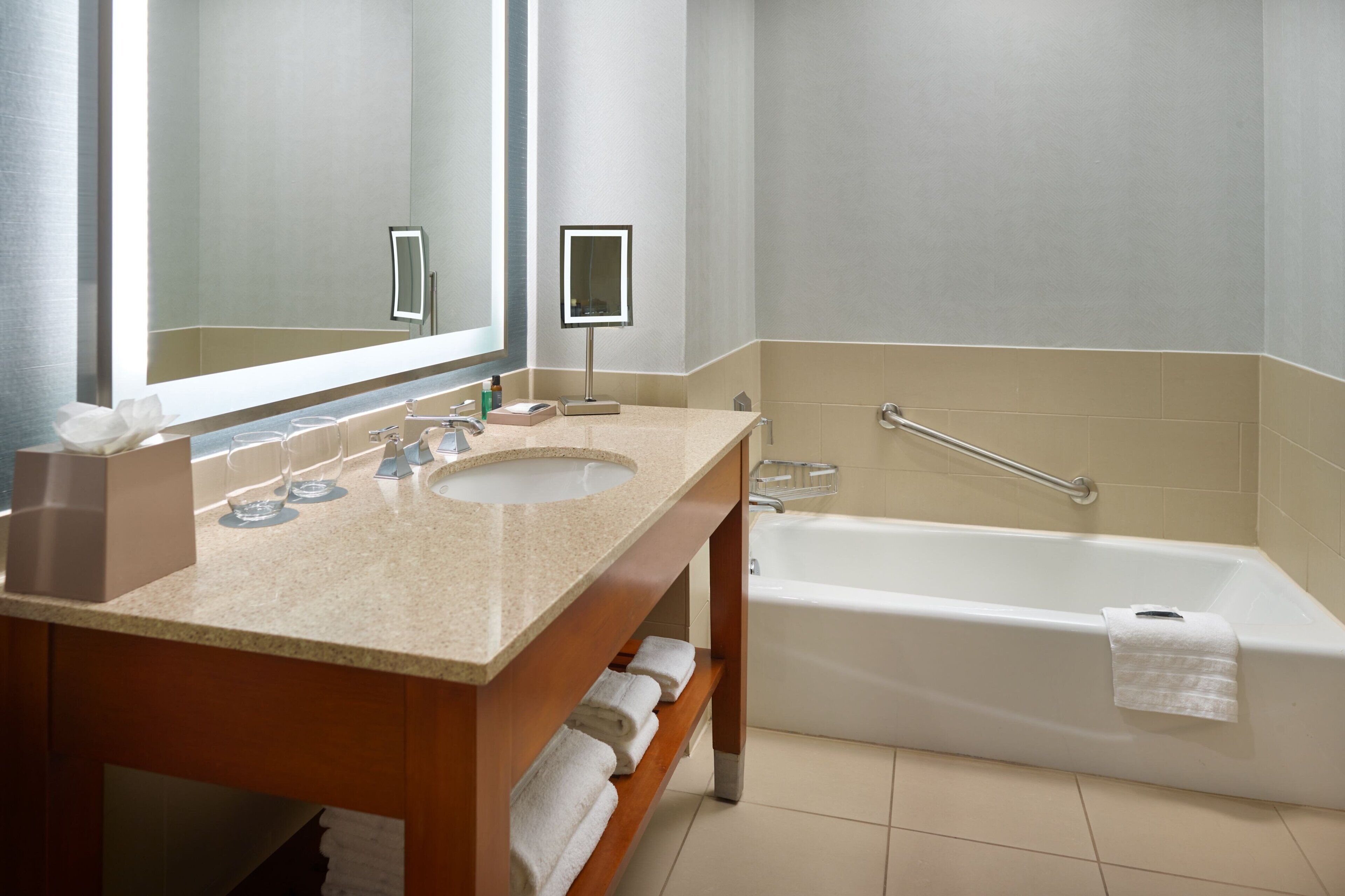 A bathroom with a large mirror, a sink, and a bathtub.