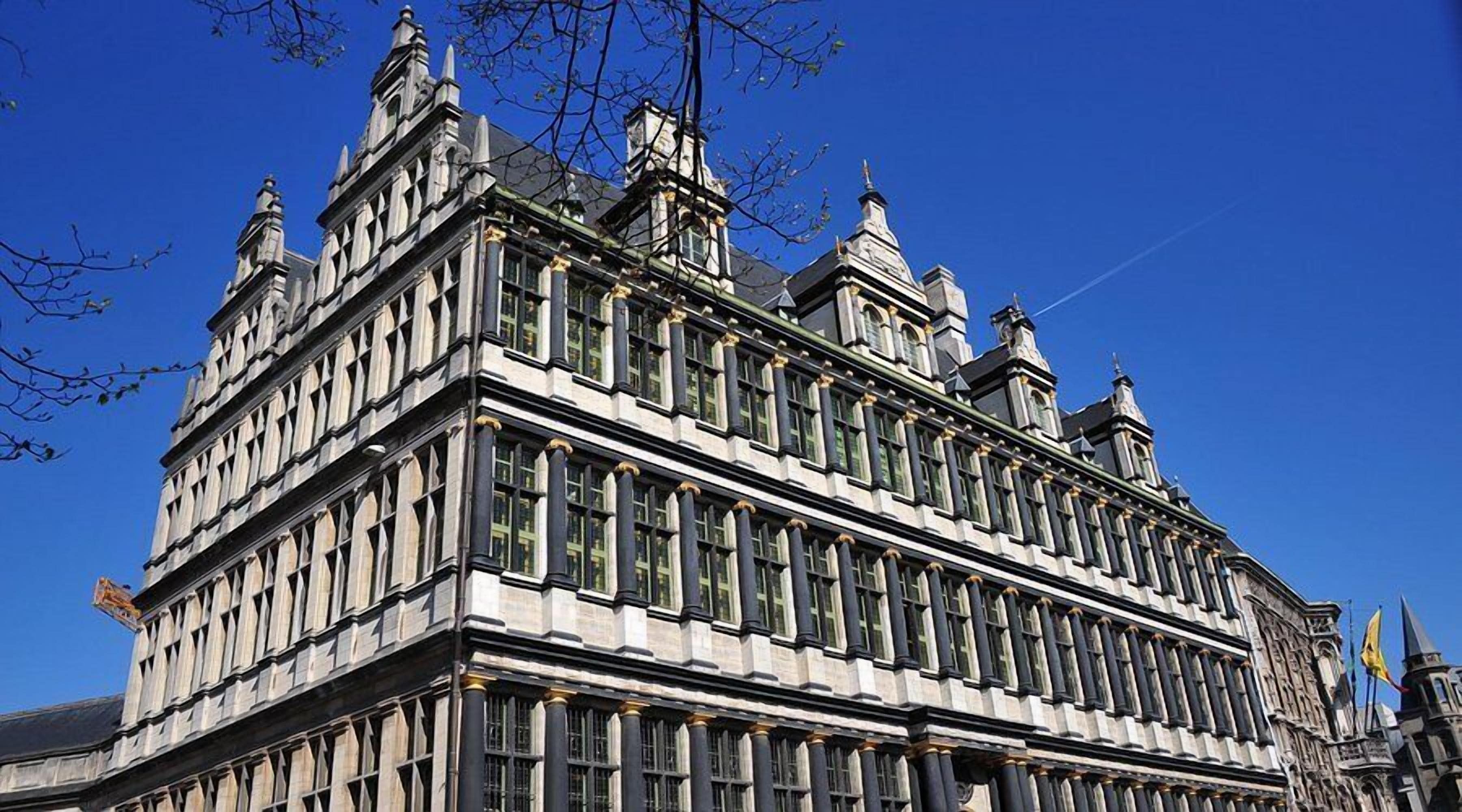Un grand bâtiment historique à étages, doté d’une façade symétrique avec des fenêtres régulièrement espacées et des éléments décoratifs.