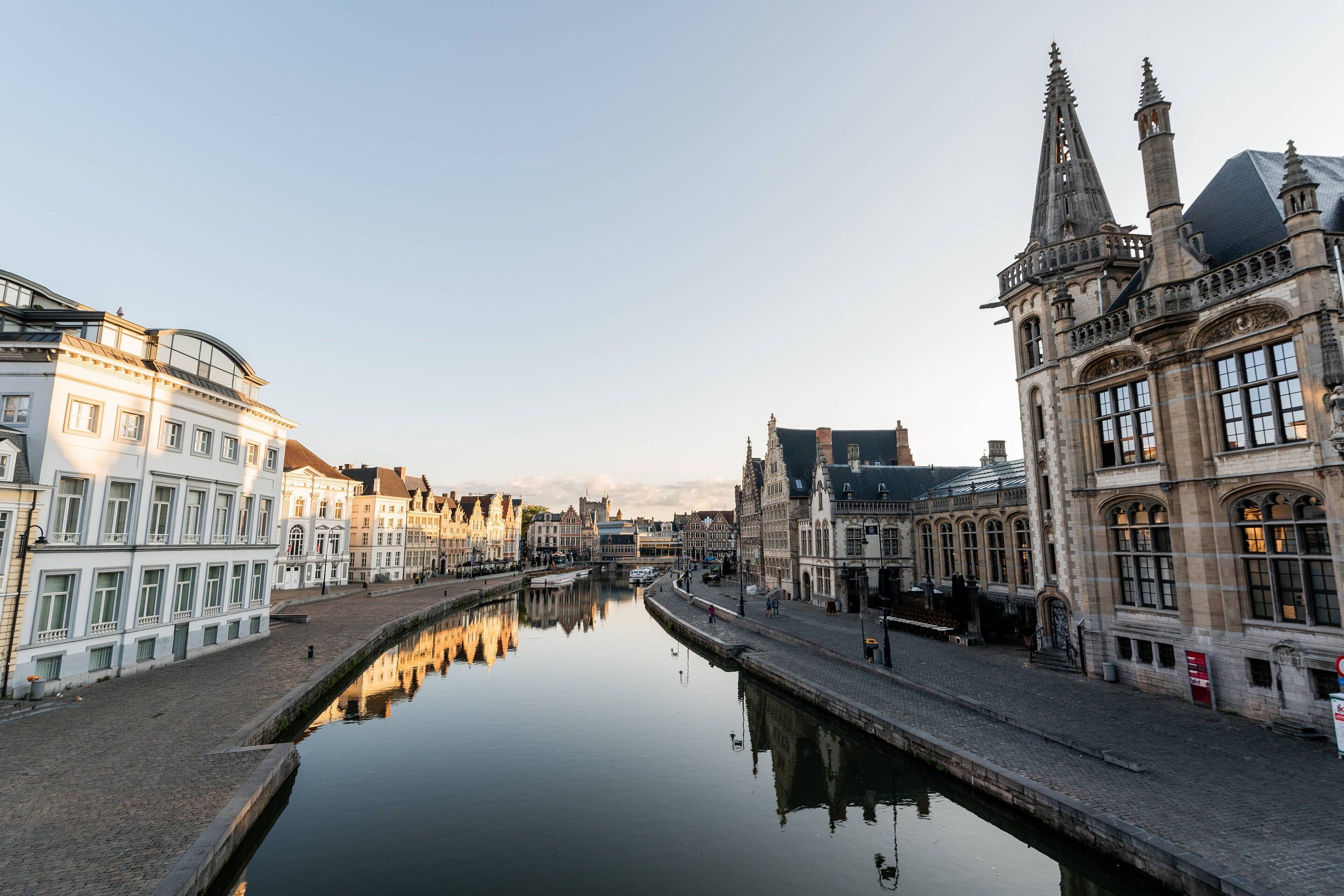 A canal with buildings on either side, including a prominent Gothic-style structure with two spires.