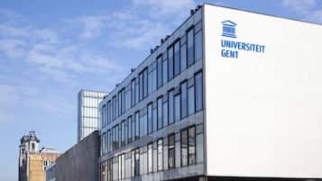 Ein modernes Gebäude mit einem auffälligen 'Universität GENT'-Schild, großen Fenstern und einer Mischung aus Glas- und Betonarchitektur.
