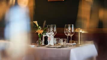 Et spisebord dækket med vinglas, en vase med blomster og en menu.