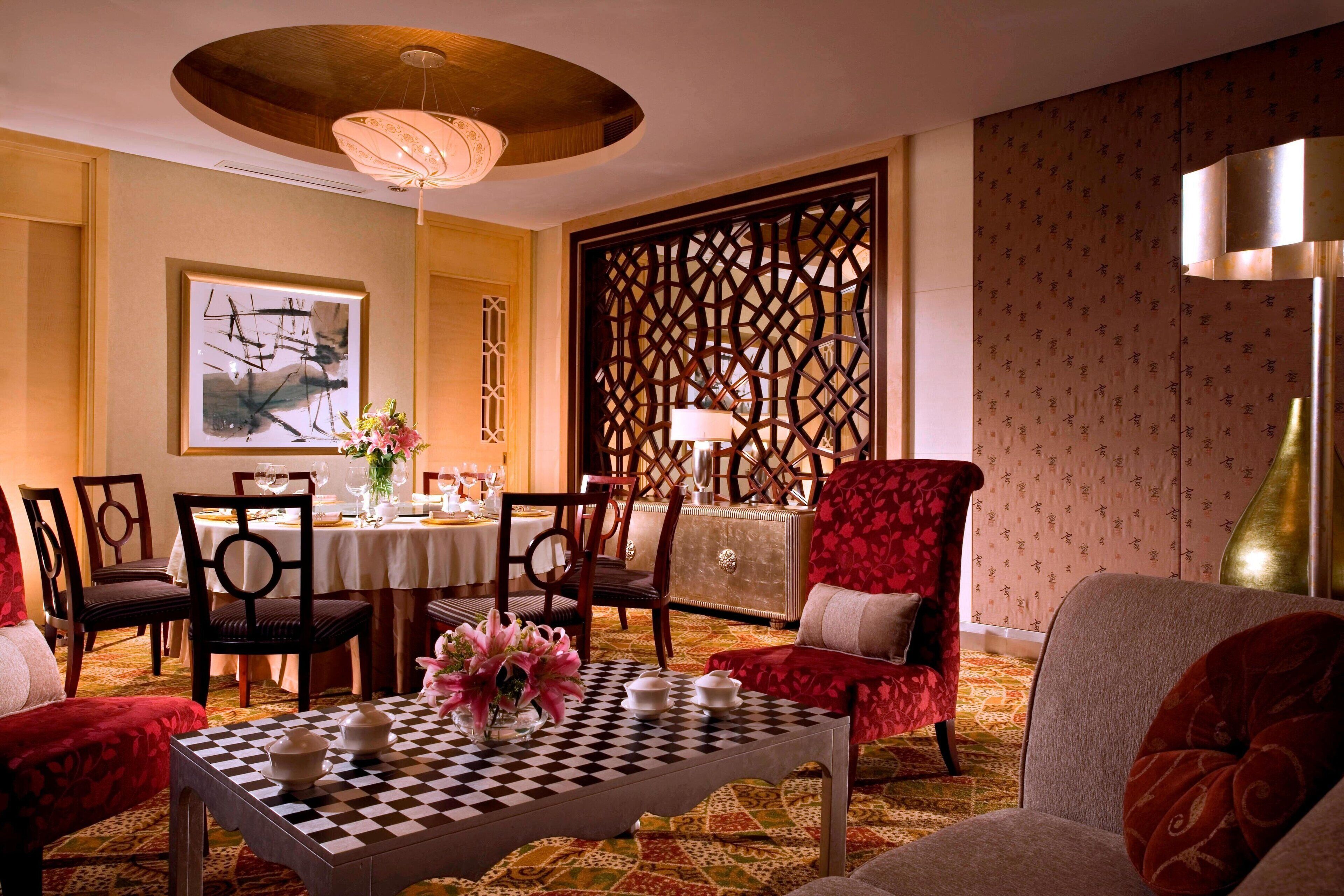 A dining area with a checkered table, chairs, and a decorative screen.