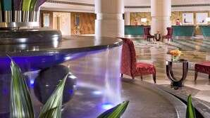 A spacious lobby with a reception desk, seating area, and a decorative fountain.