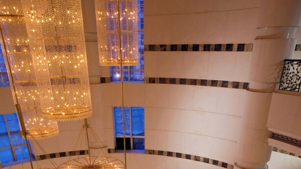 A multi-level atrium with a geometric patterned floor, multiple hanging light fixtures, and a central decorative element.