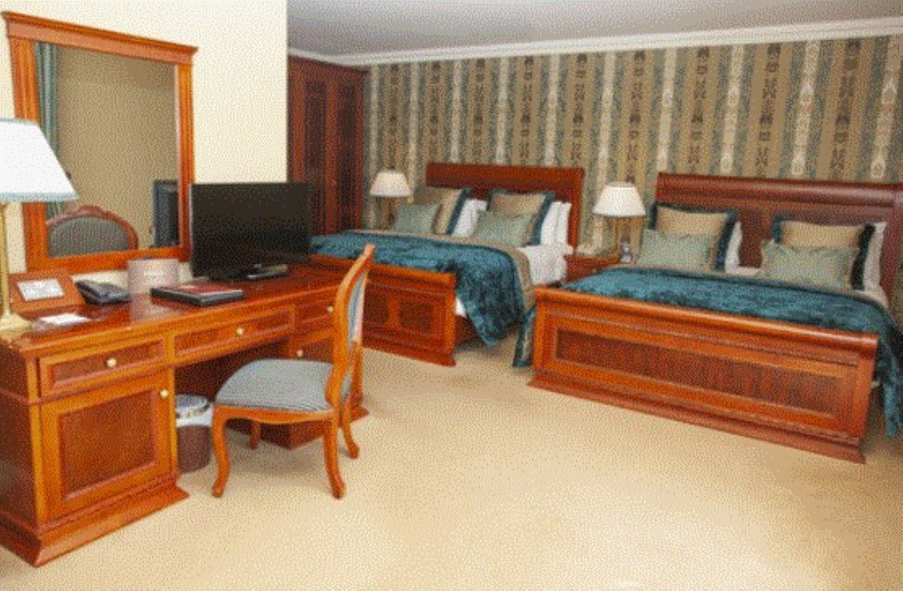 A hotel room with two beds, a desk with a computer, a chair, and a television.