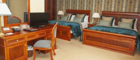 A hotel room with two beds, a desk with a computer, a chair, and a television.