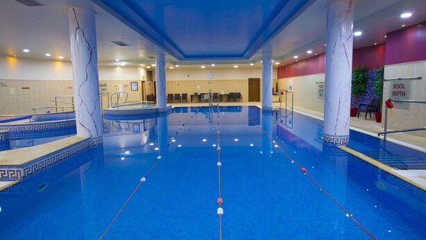 A large indoor swimming pool with clear lanes, a changing room area, and a pool depth sign. - Knightsbrook Hotel Spa & Golf Resort (Trim)