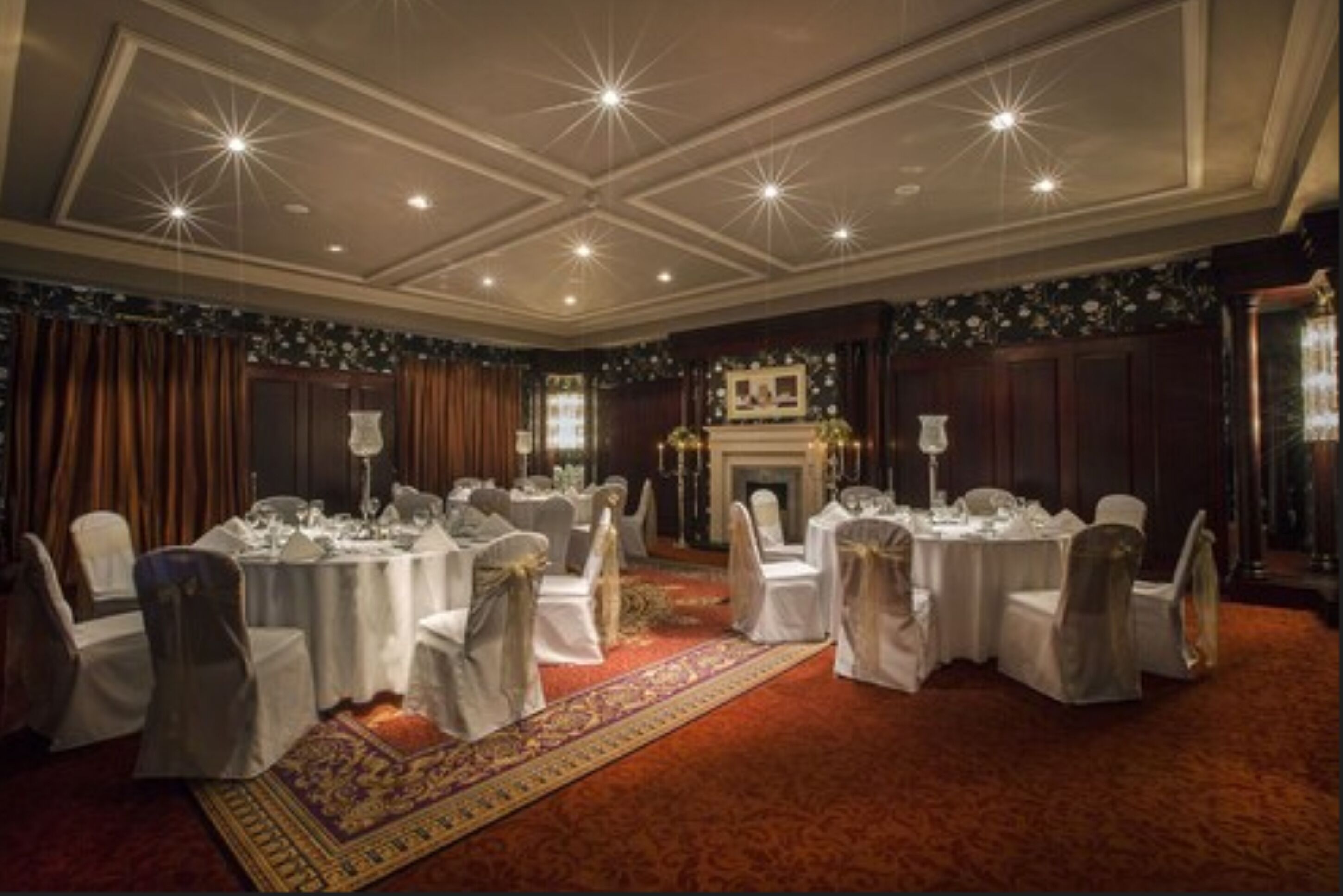 Un salón de banquetes con mesas redondas, manteles blancos y sillas con lazos.