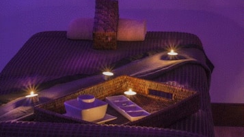 Una habitación con una cama, una bandeja con velas y una botella.