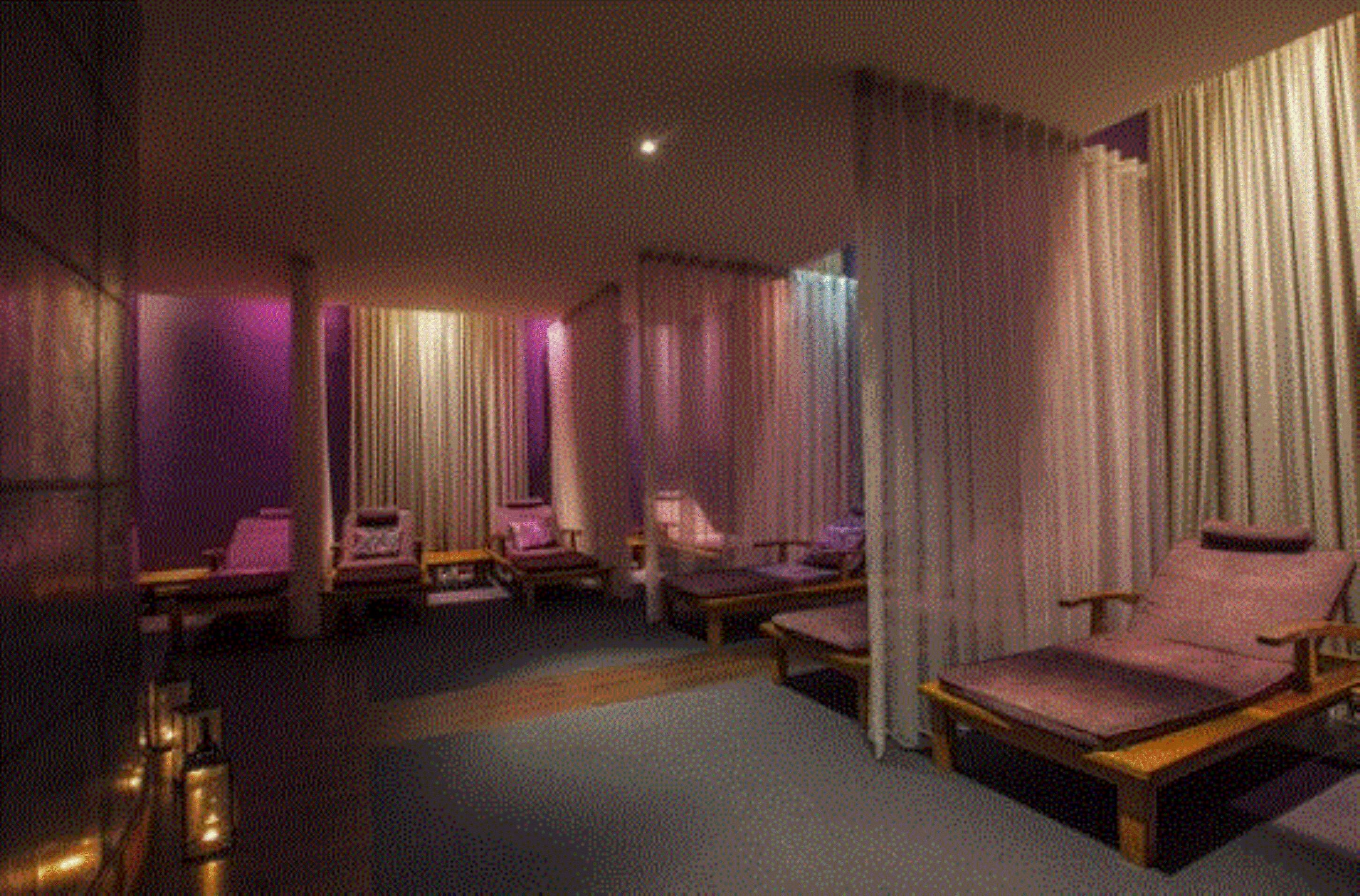 A room with multiple seating areas, including a large bed and several chairs.