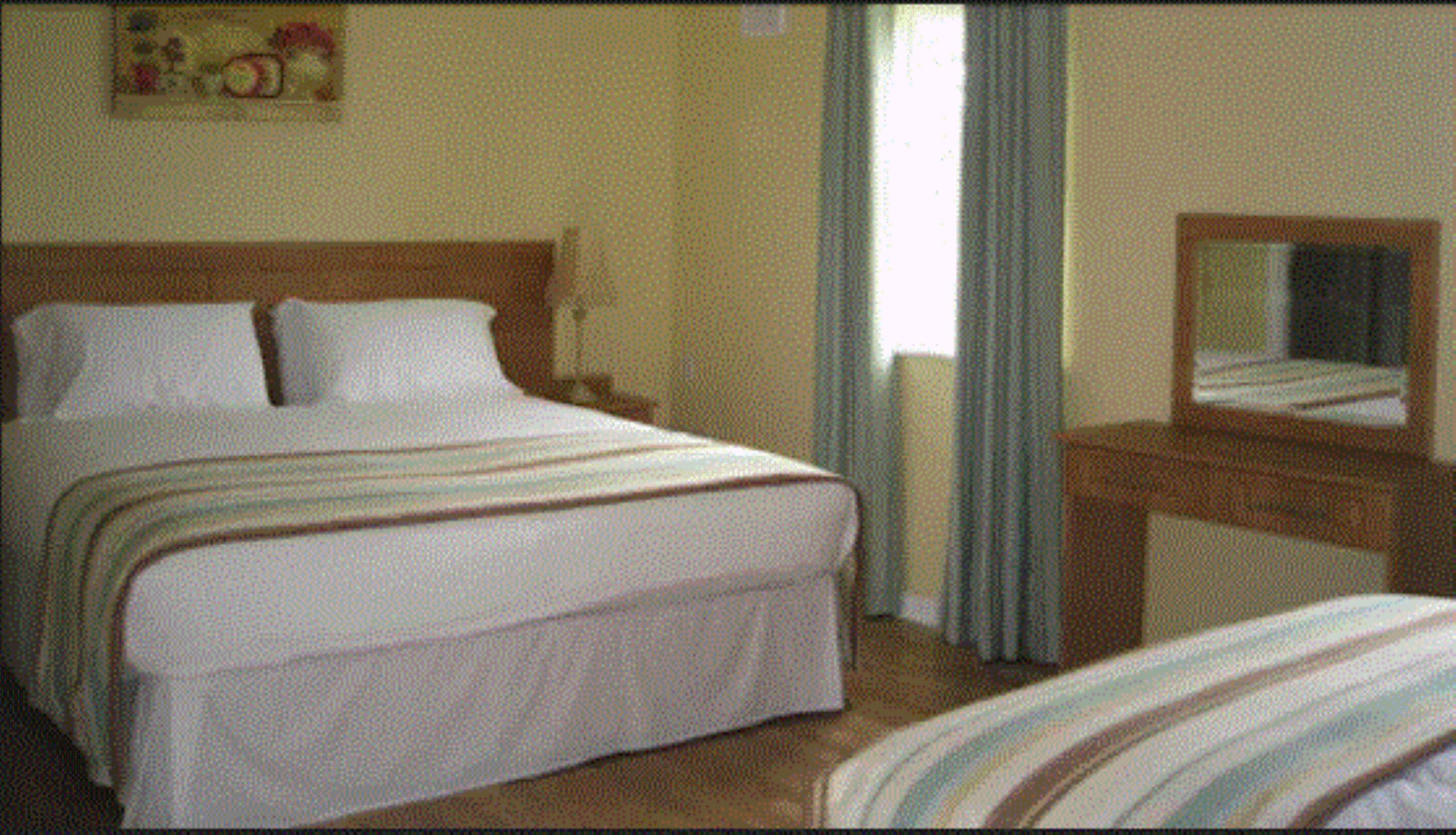 A hotel room with a large bed, a bedside table, a dresser, and a mirror.