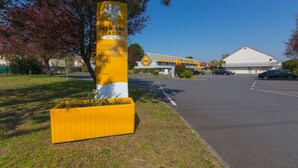 Un panneau jaune avec l’inscription « Premiere Classe Hotels » et un bâtiment en arrière-plan.