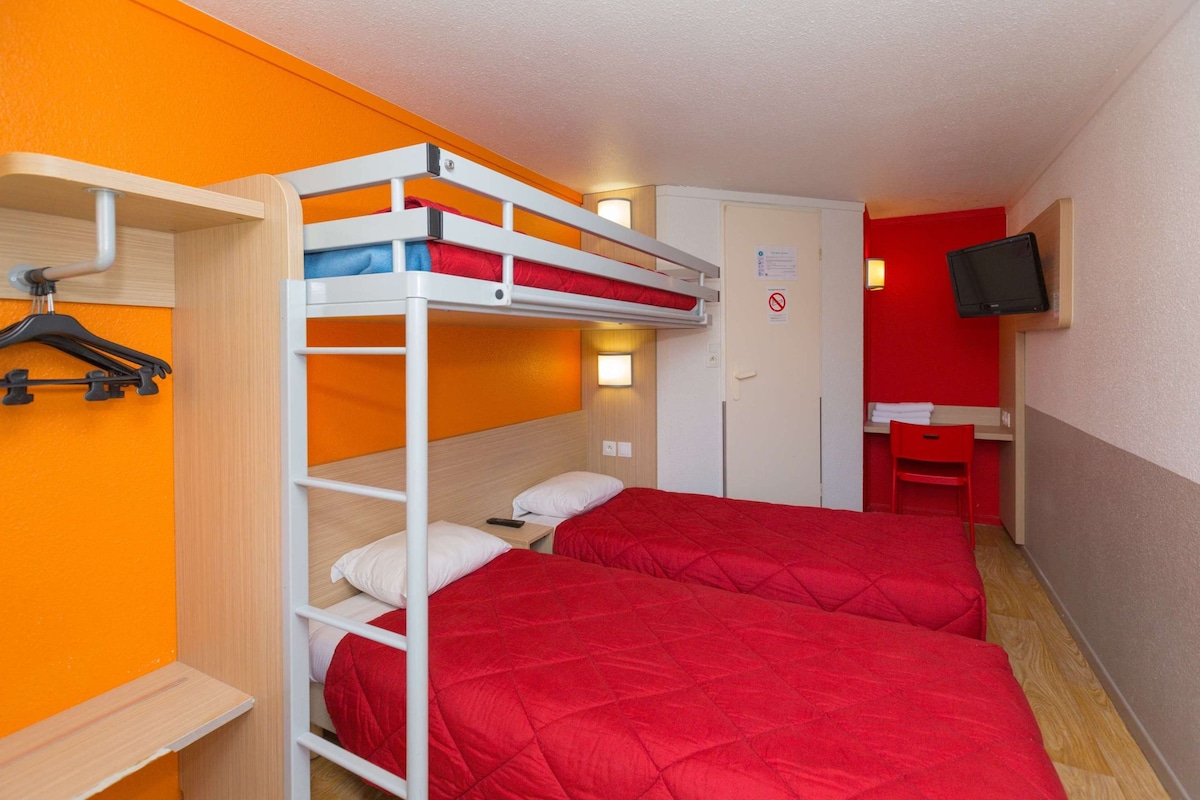 Habitación con literas, paredes naranja, un escritorio y una televisión.